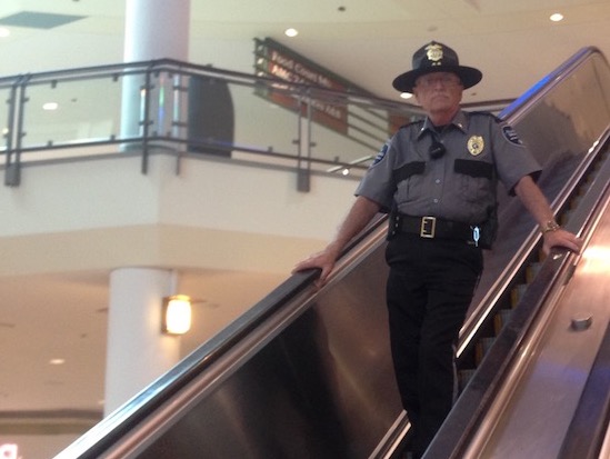 Security Officer Descending Mall Escalator